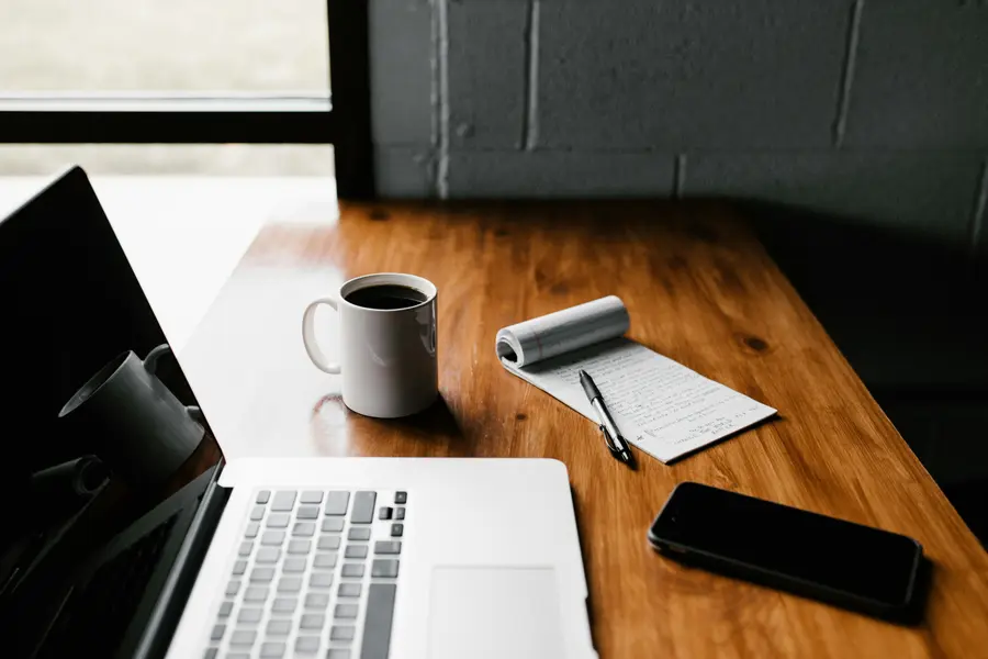 Escritorio de trabajo con laptop, café y libreta